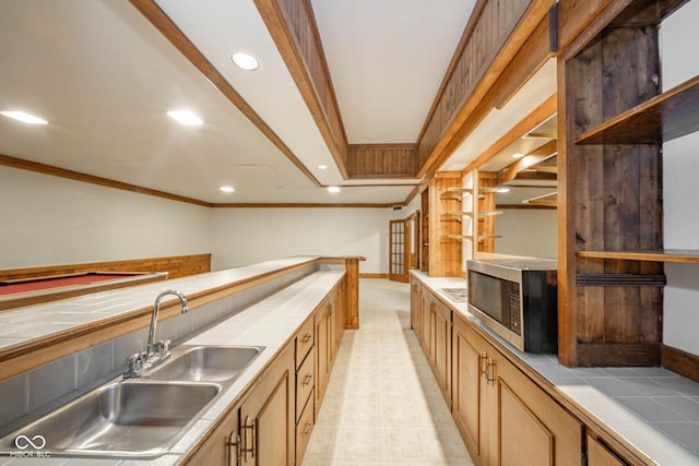 kitchen featuring tile counters, stainless steel microwave, recessed lighting, and a sink