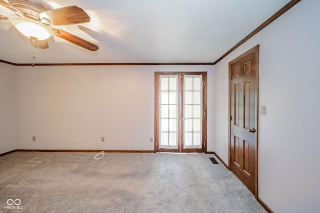 carpeted spare room with baseboards, ornamental molding, ceiling fan, and visible vents