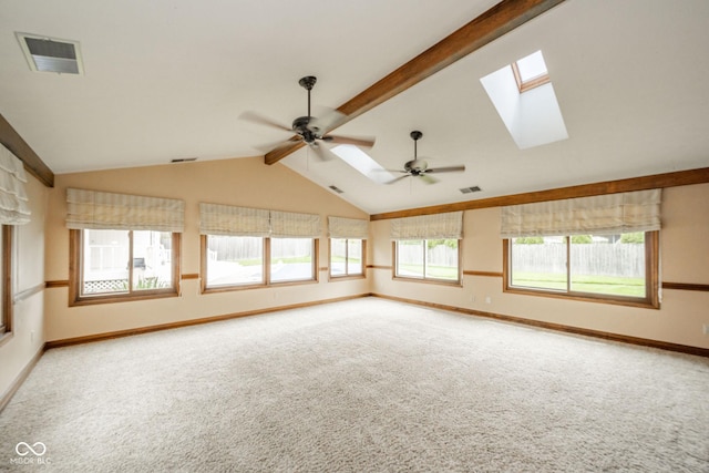 carpeted empty room with a ceiling fan, baseboards, visible vents, and vaulted ceiling with skylight