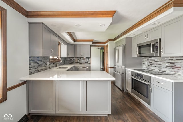 kitchen featuring backsplash, crown molding, appliances with stainless steel finishes, a sink, and a peninsula