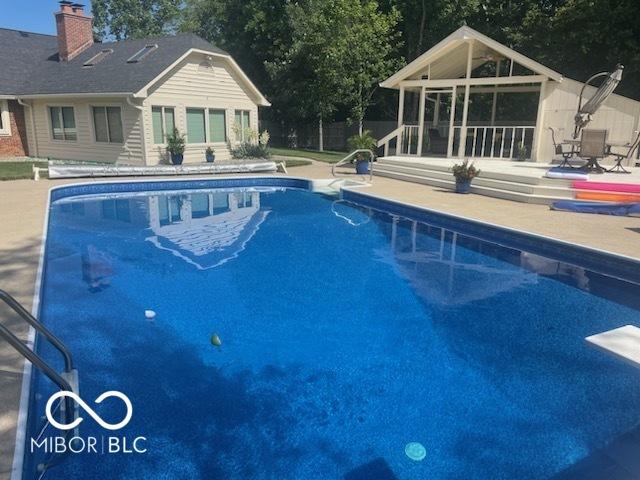 pool with a diving board and a patio area