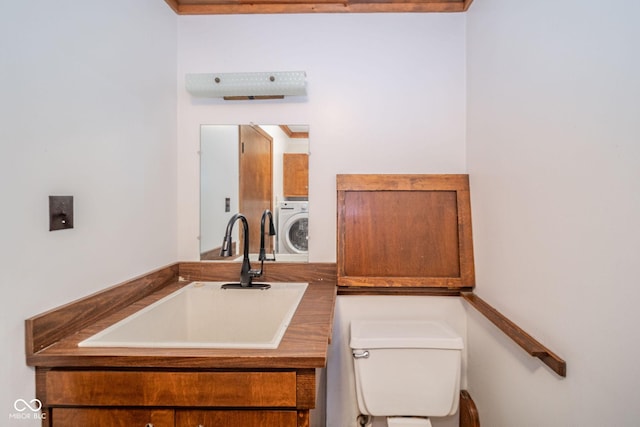 bathroom with washer / dryer, toilet, and a sink