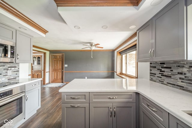 kitchen featuring stainless steel appliances, a ceiling fan, a peninsula, backsplash, and gray cabinetry