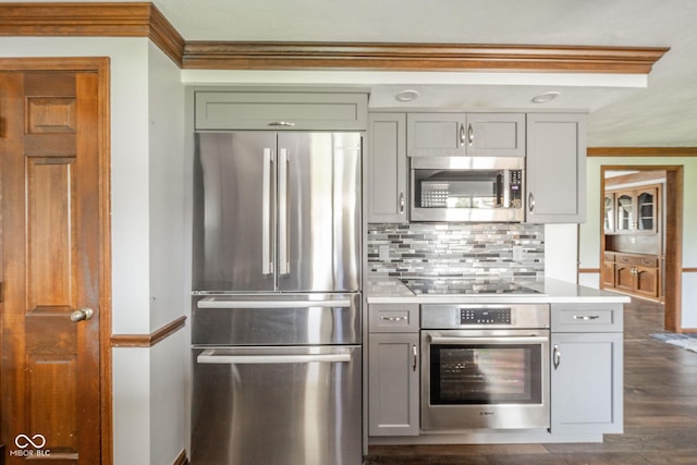 kitchen featuring light countertops, stainless steel appliances, decorative backsplash, gray cabinetry, and ornamental molding