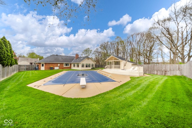 view of pool featuring a lawn, a deck, a fenced backyard, and a diving board