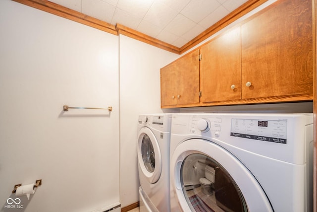 laundry room featuring crown molding, cabinet space, and washer and clothes dryer