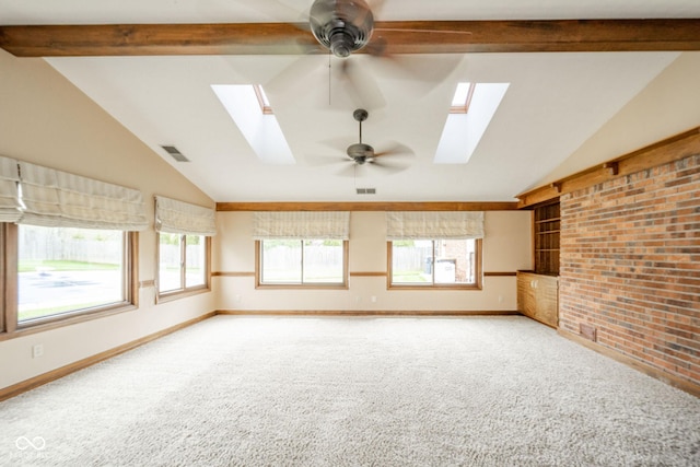 unfurnished room with visible vents, lofted ceiling with skylight, ceiling fan, and carpet flooring