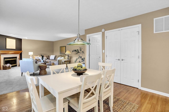10746 Gateway Dr, Fishers, IN 46037 - dining area featuring light wood-style floors, a fireplace, and baseboards