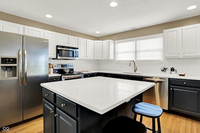 10746 Gateway Dr, Fishers, IN 46037 - kitchen featuring appliances with stainless steel finishes, a sink, a breakfast bar area, white cabinetry, and backsplash