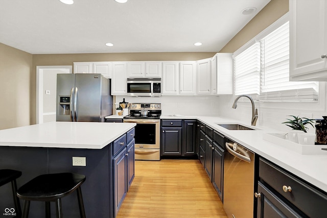 10746 Gateway Dr, Fishers, IN 46037 - kitchen with appliances with stainless steel finishes, a sink, white cabinets, a kitchen bar, and recessed lighting