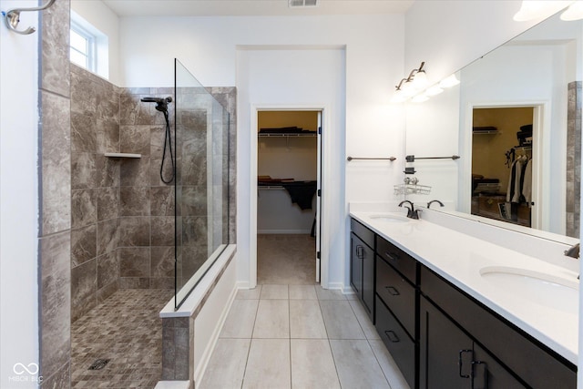 bathroom featuring tile patterned flooring, a sink, a walk in shower, and double vanity