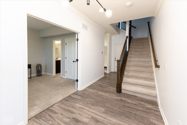 stairs featuring baseboards, visible vents, ornamental molding, and wood finished floors