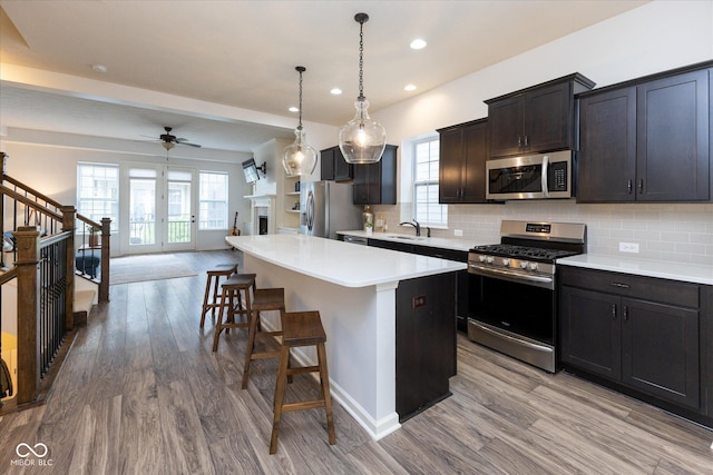 kitchen featuring a breakfast bar area, appliances with stainless steel finishes, a sink, light wood-style floors, and recessed lighting