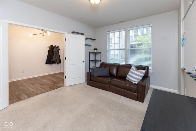 carpeted living area with baseboards, wood finished floors, and visible vents