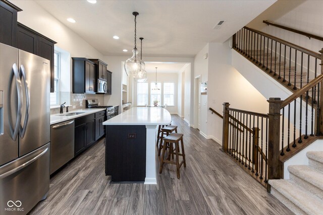 kitchen with dark wood-type flooring, a sink, an island with sink, and stainless steel appliances