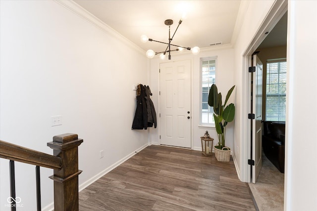 foyer entrance featuring a notable chandelier, baseboards, wood finished floors, visible vents, and ornamental molding