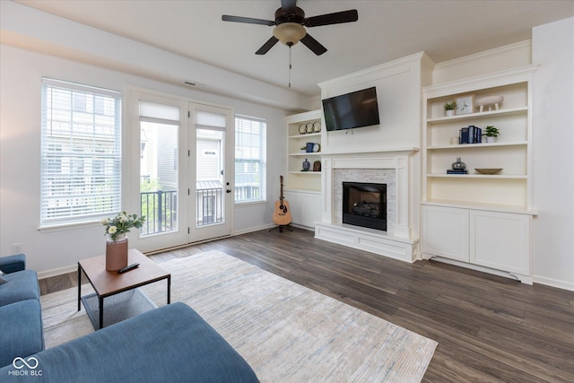 living area with a ceiling fan, baseboards, dark wood-style floors, and a fireplace