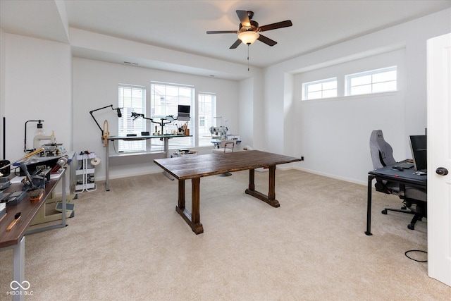 office space with a healthy amount of sunlight, baseboards, light carpet, and a ceiling fan
