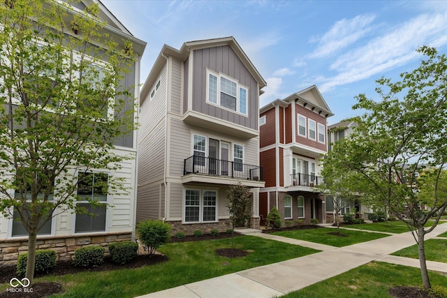 view of front of home featuring board and batten siding, a front yard, and stone siding