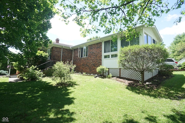 314 Olive St, Batesville, IN 47006 - view of property exterior featuring a yard, brick siding, and a chimney