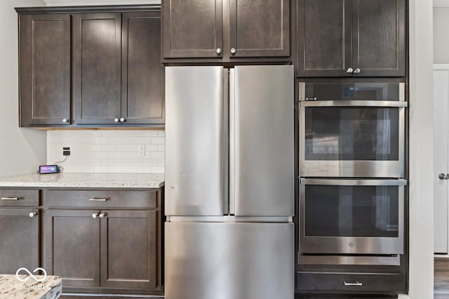 5363 Citadel Dr, Noblesville, IN 46062 - kitchen featuring stainless steel appliances, dark brown cabinets, tasteful backsplash, and light stone countertops