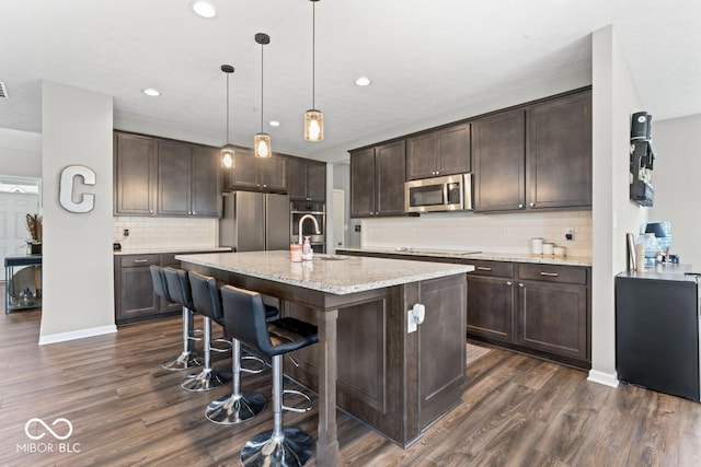 5363 Citadel Dr, Noblesville, IN 46062 - kitchen featuring stainless steel appliances, a sink, dark brown cabinets, dark wood-type flooring, and tasteful backsplash