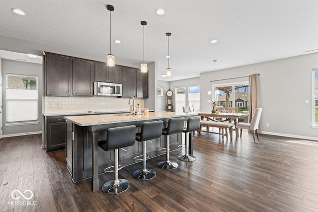 5363 Citadel Dr, Noblesville, IN 46062 - kitchen with stainless steel microwave, dark wood-style flooring, a sink, backsplash, and baseboards