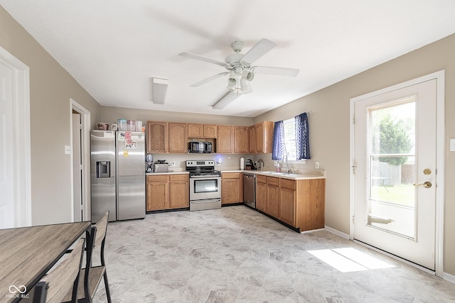 kitchen with brown cabinets, ceiling fan, appliances with stainless steel finishes, a sink, and light countertops