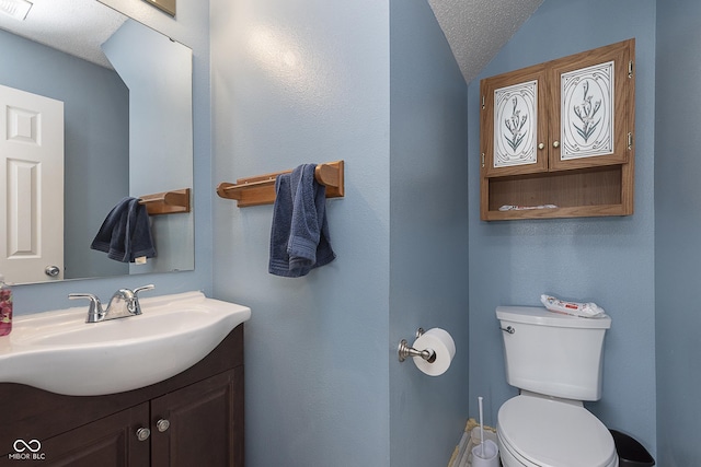 half bathroom featuring vanity, visible vents, toilet, and lofted ceiling