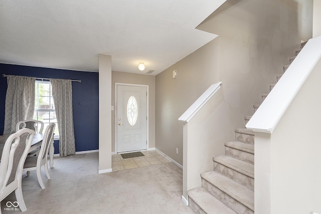 carpeted foyer featuring baseboards and stairway