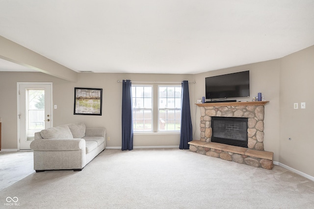 living area featuring carpet floors, baseboards, and a stone fireplace