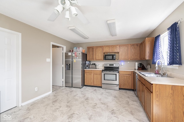 kitchen with a sink, light countertops, brown cabinets, a ceiling fan, and appliances with stainless steel finishes