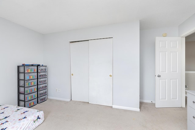 carpeted bedroom with a closet and baseboards