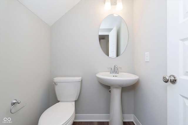 bathroom with baseboards, toilet, wood finished floors, and lofted ceiling