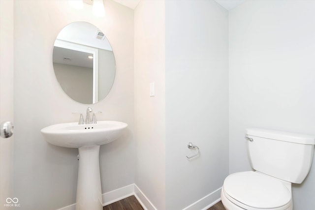 half bath featuring baseboards, toilet, wood finished floors, and visible vents