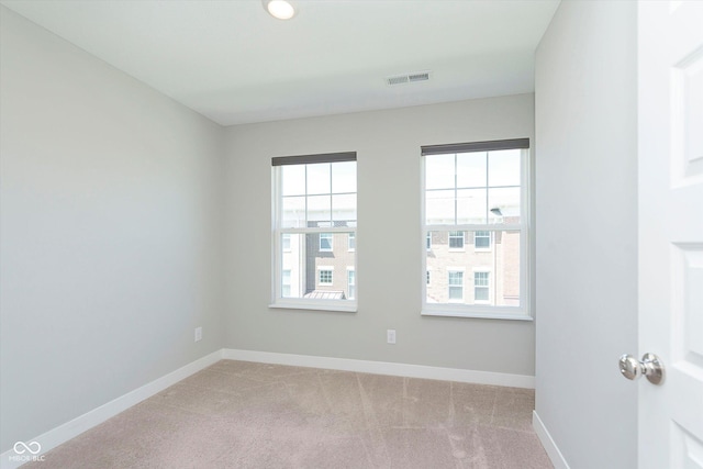 unfurnished room featuring visible vents, baseboards, and light colored carpet