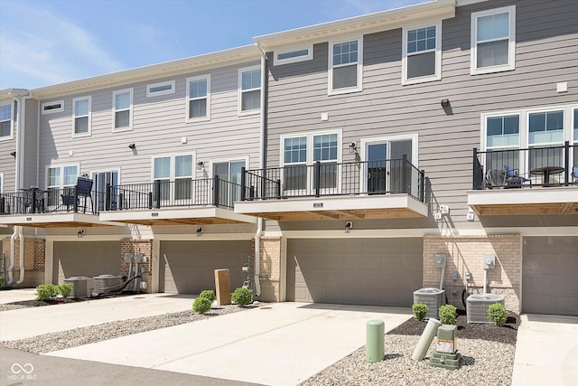 exterior space with a garage, central AC, and concrete driveway