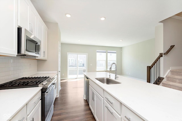 kitchen featuring decorative backsplash, appliances with stainless steel finishes, a sink, dark wood-style floors, and white cabinetry