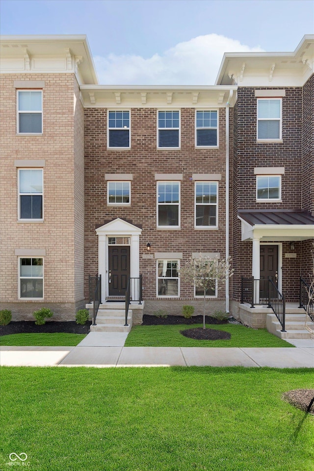 view of property with brick siding and a front lawn