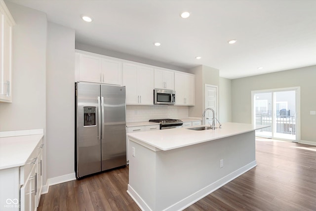 kitchen with dark wood-style flooring, appliances with stainless steel finishes, a sink, baseboards, and decorative backsplash