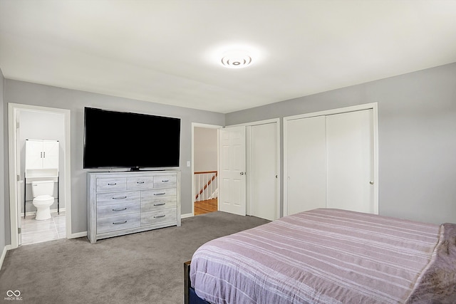 bedroom featuring carpet flooring, baseboards, multiple closets, and ensuite bathroom