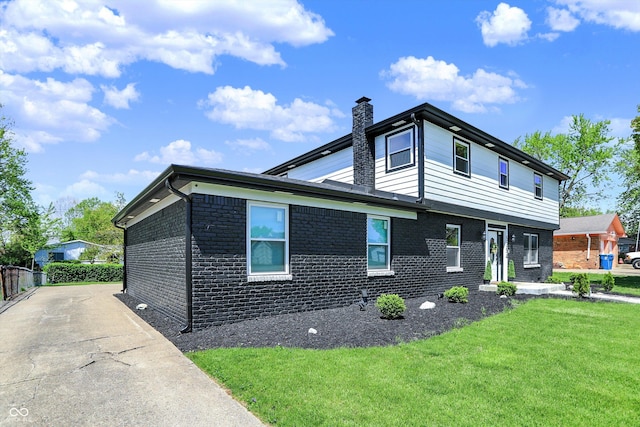 view of front of house featuring fence, a chimney, a front lawn, and brick siding