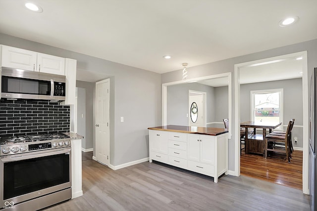 kitchen featuring decorative backsplash, light wood-style floors, recessed lighting, white cabinetry, and appliances with stainless steel finishes