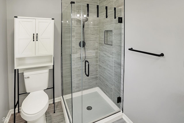 bathroom featuring baseboards, a stall shower, and toilet