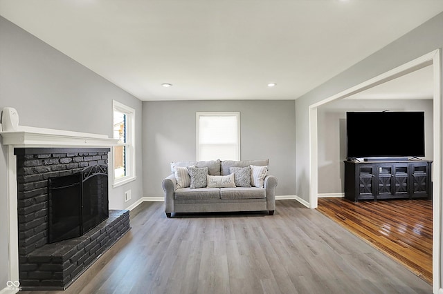 living room with baseboards, recessed lighting, a brick fireplace, and wood finished floors