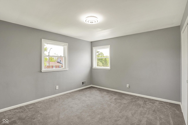 empty room featuring baseboards, carpet, and visible vents