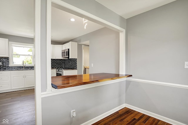 kitchen with baseboards, dark wood-style floors, white cabinetry, tasteful backsplash, and appliances with stainless steel finishes