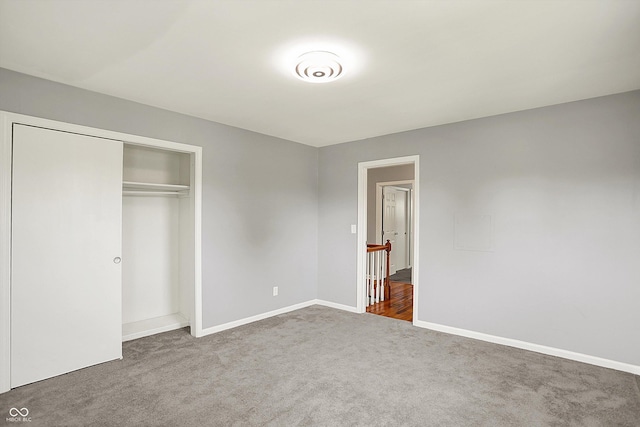 unfurnished bedroom featuring carpet floors, baseboards, and a closet