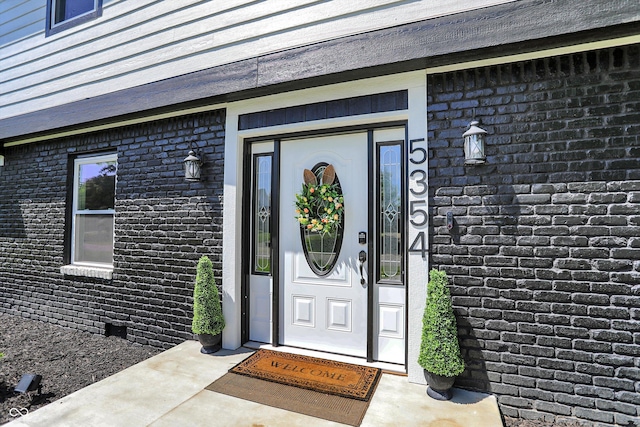 entrance to property featuring brick siding and crawl space