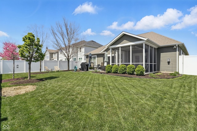 rear view of property featuring a sunroom, a fenced backyard, and a lawn